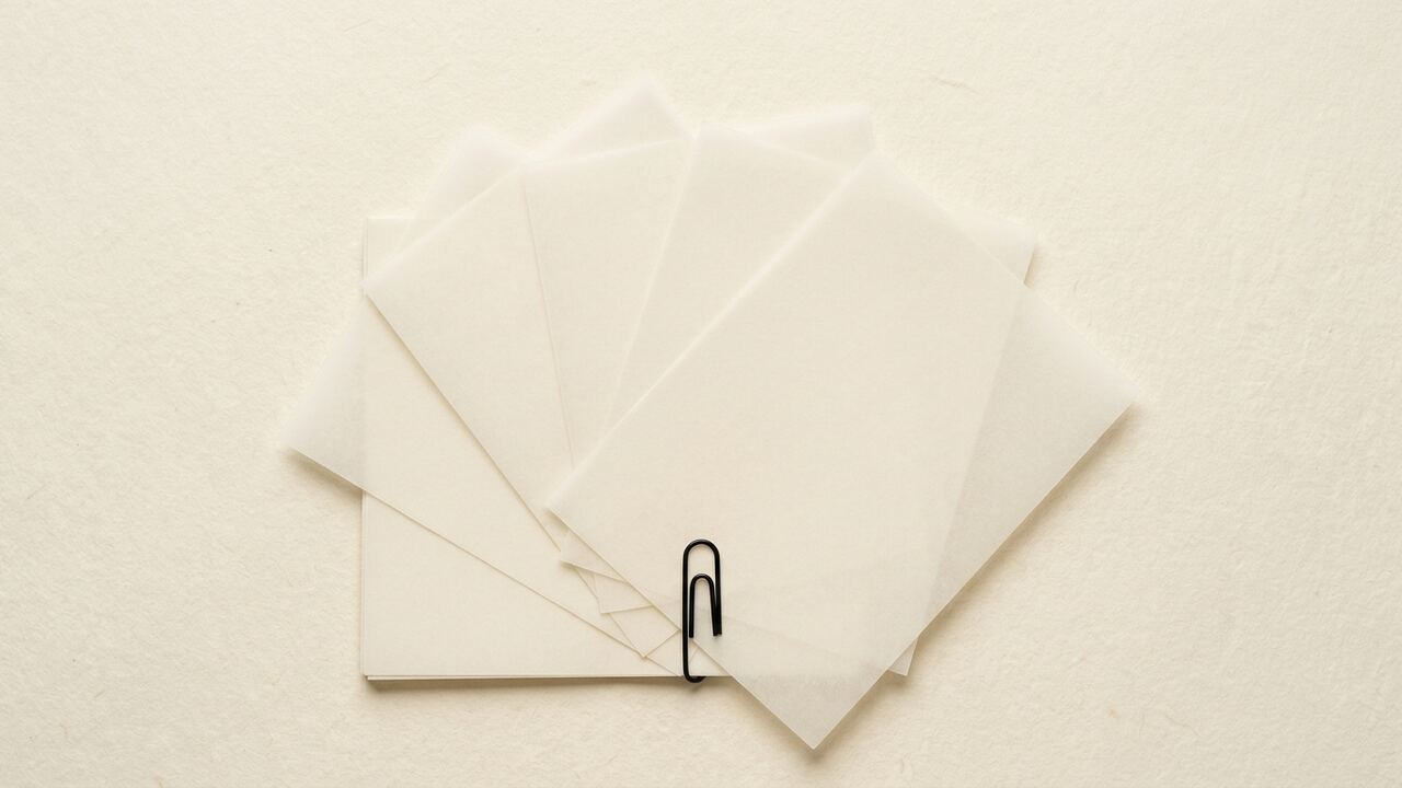 Illustrative brand image, synthetic: six blank translucent vellum sheets fanned from a single squared stack, held at one corner by a paperclip